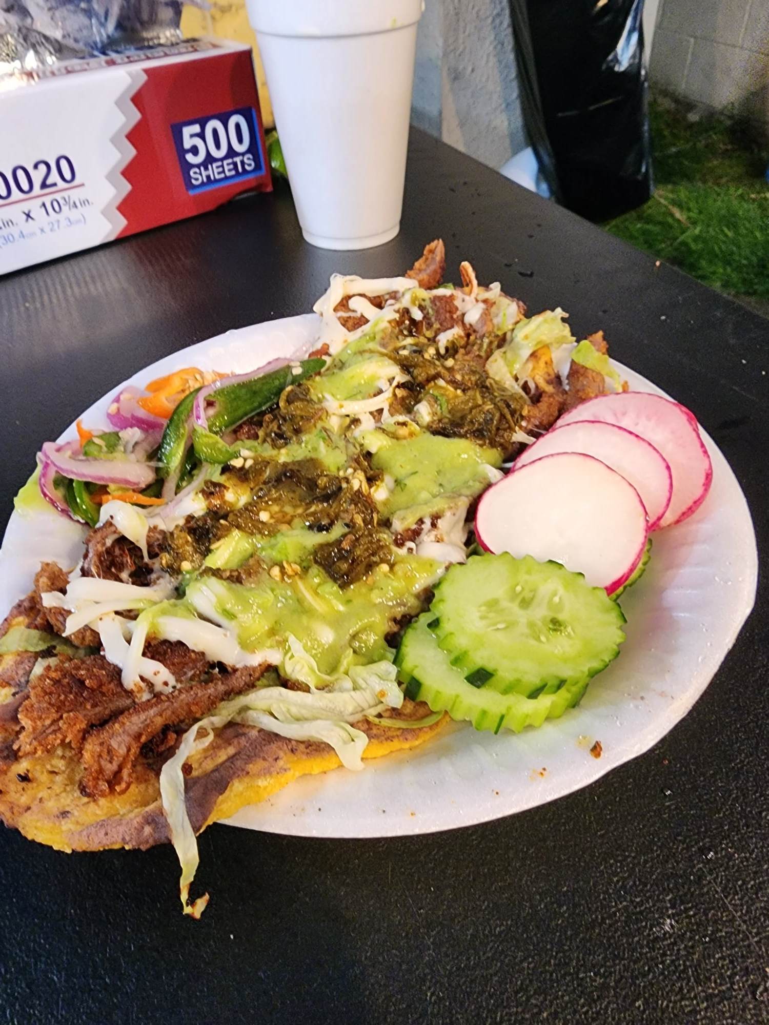 Huarache topped with meat and vegetables